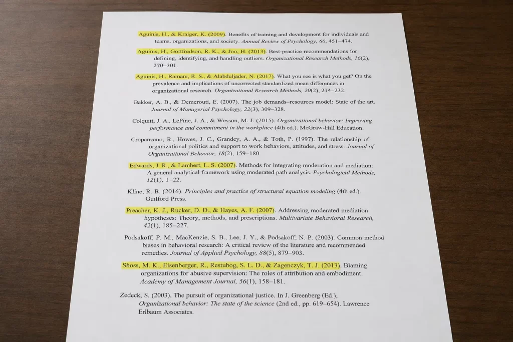 Widok z góry na bibliografię artykułu naukowego, w której część nazwisk autorów jest wielokrotnie podkreślona lub zaznaczona, podczas gdy inne nie mają żadnych oznaczeń, jasne oświetlenie biurowe.