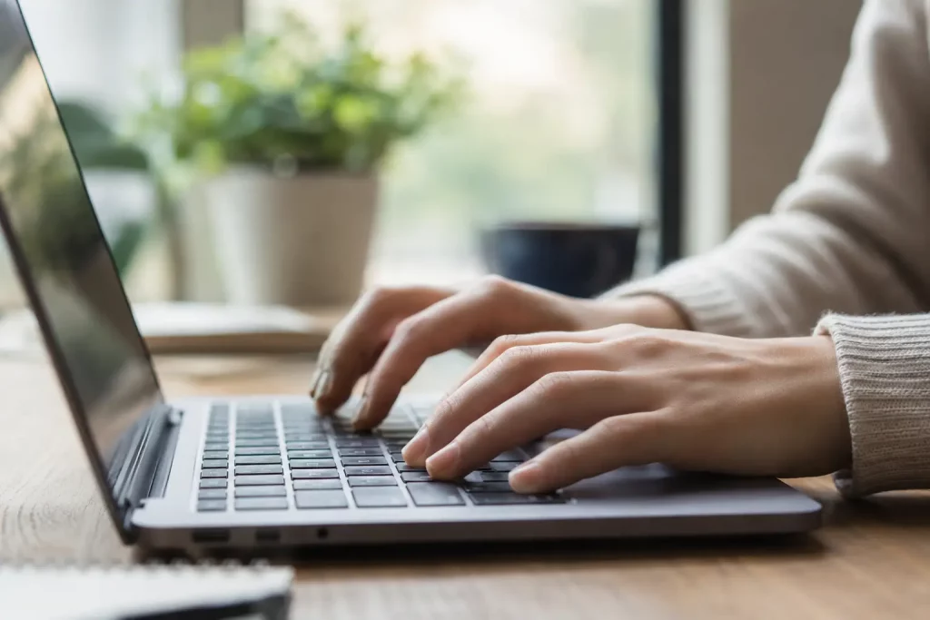 dłonie pisane na klawiaturze laptopa